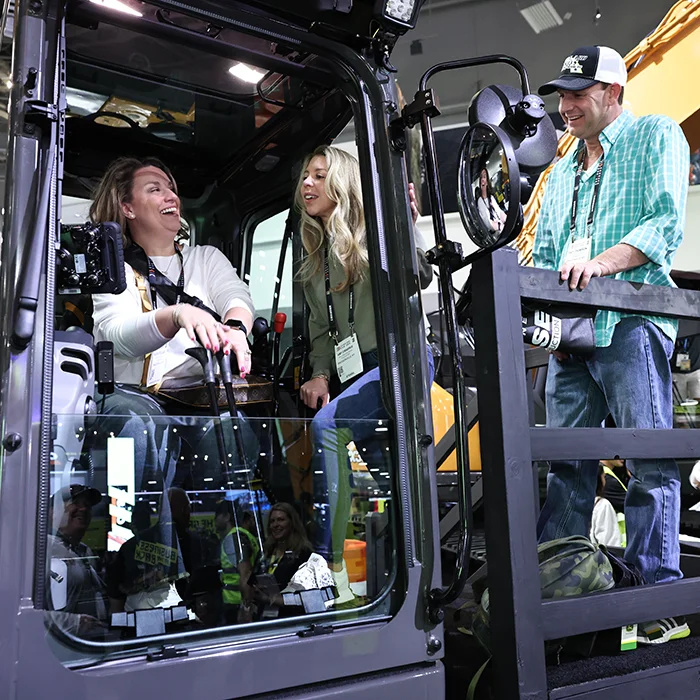 Two women and a man in the cabin of construction equipment