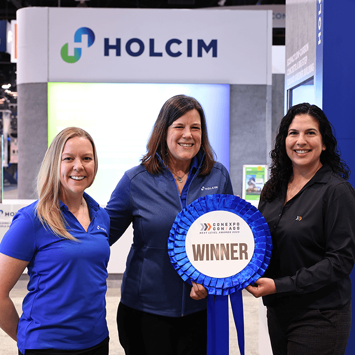 Two women accepting a ribbon award for Next Level Awards from CONEXPO-CON/AGG
