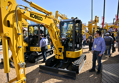 Mini Kobelco excavator with people looking at it