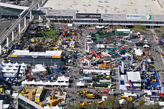 Aerial view of an CONEXPO-CON/AGG expo with booths, tents, heavy machinery, and crowds