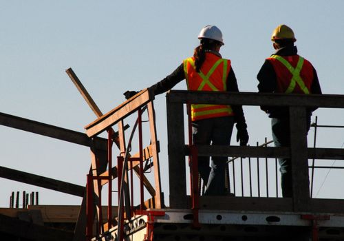 Women and man on a construction site with hard hat and orange vest