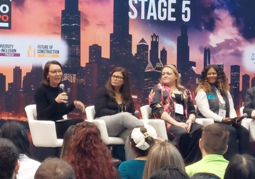 A diverse group of women in construction sitting on stage at a conference.
