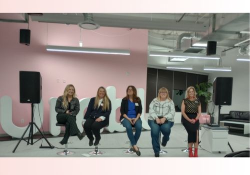 A diverse group of women in construction sitting in chairs on a stage