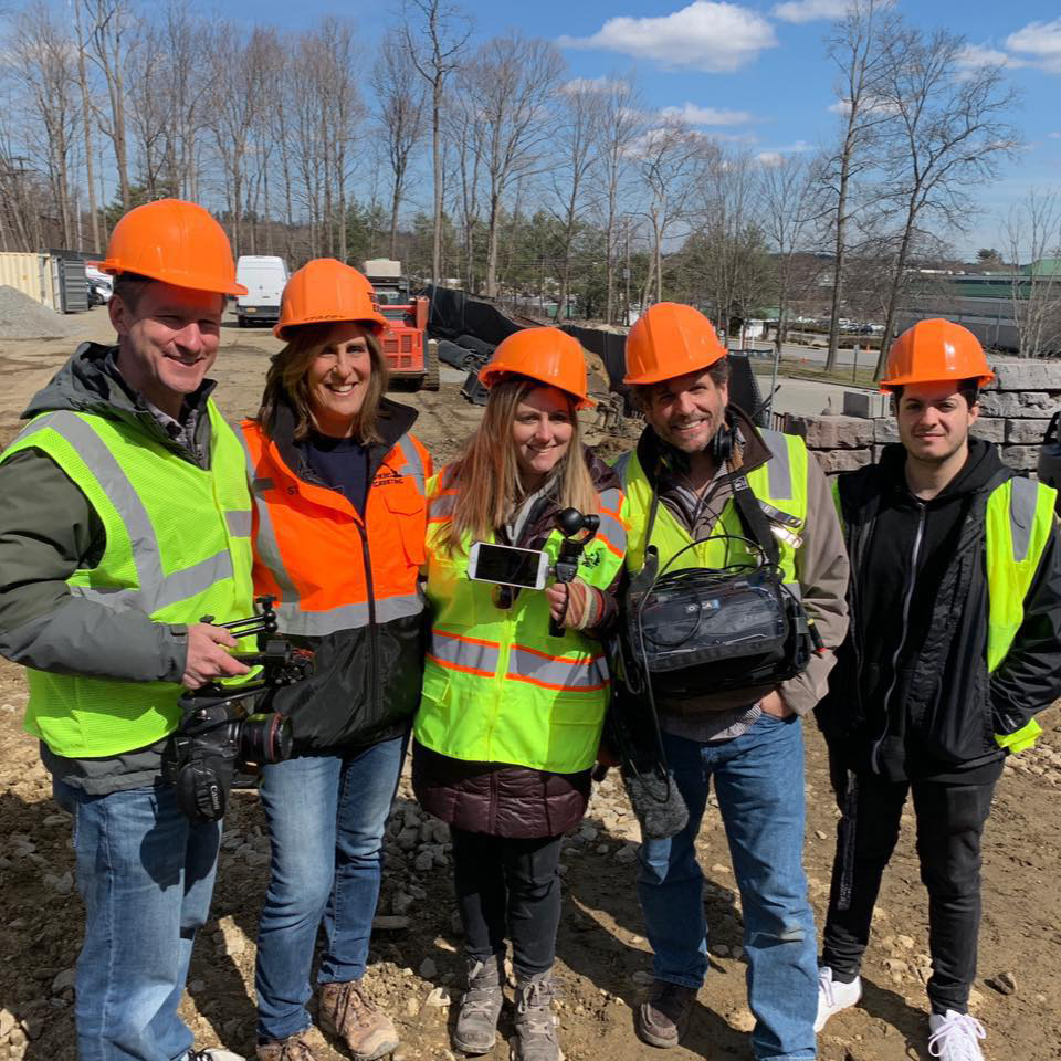 Stacey Topmpkins and team at work posing for a picture with hard hats and reflective vests on