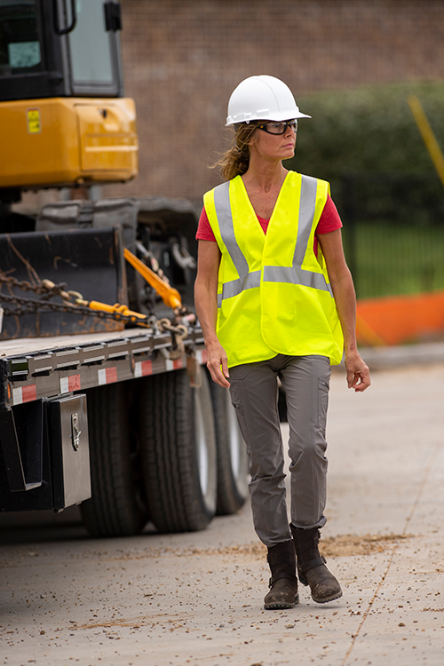 Person walking with construction equipment in the background.