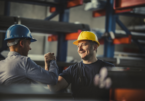 Happy metal worker greeting his manager in aluminum mill.